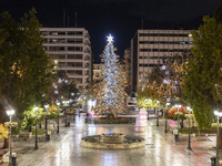 Festive night view of the iconic Syntagma Square adorned with dazzling Christmas decorations, featuring a towering Christmas tree illuminate...