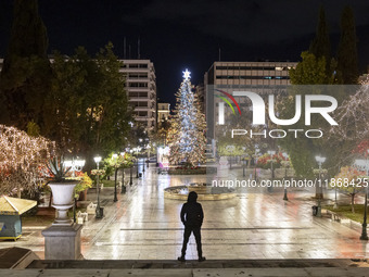 Festive night view of the iconic Syntagma Square adorned with dazzling Christmas decorations, featuring a towering Christmas tree illuminate...