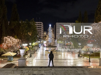 Festive night view of the iconic Syntagma Square adorned with dazzling Christmas decorations, featuring a towering Christmas tree illuminate...