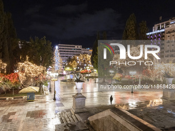 Festive night view of the iconic Syntagma Square adorned with dazzling Christmas decorations, featuring a towering Christmas tree illuminate...