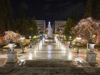 Festive night view of the iconic Syntagma Square adorned with dazzling Christmas decorations, featuring a towering Christmas tree illuminate...