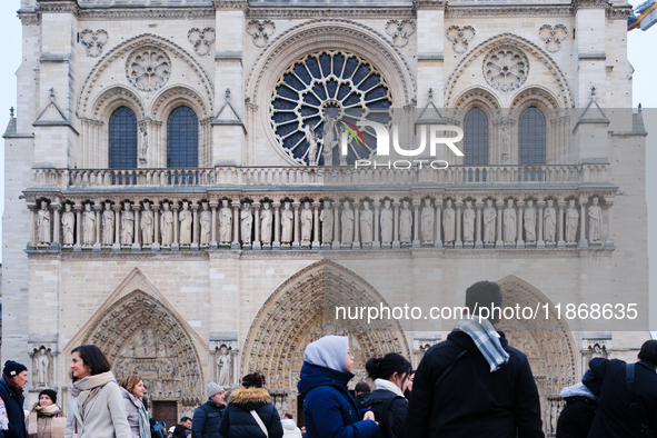 People stand in front of Notre Dame Cathedral in Paris, on december 14, 2024. 