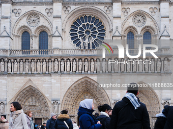 People stand in front of Notre Dame Cathedral in Paris, on december 14, 2024. (