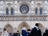 People stand in front of Notre Dame Cathedral in Paris, on december 14, 2024. (