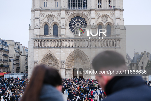 A couple and the crowd press on the forecourt of Notre-Dame Cathedral in Paris, on december 14, 2024. 