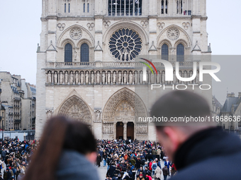 A couple and the crowd press on the forecourt of Notre-Dame Cathedral in Paris, on december 14, 2024. (