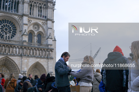 A couple stands on the forecourt of Notre-Dame Cathedral. 