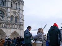 A couple stands on the forecourt of Notre-Dame Cathedral. (