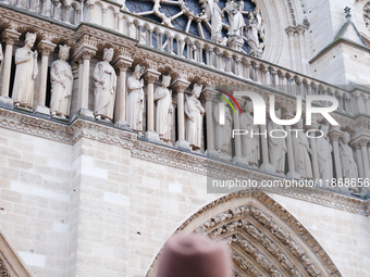 People stand in front of Notre Dame Cathedral in Paris, on december 14, 2024. (