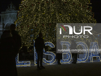 People gather around the Christmas lights at Praca do Comercio in Lisbon, Portugal, on December 14, 2024. The Christmas lights in Lisbon are...