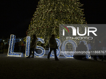 People gather around the Christmas lights at Praca do Comercio in Lisbon, Portugal, on December 14, 2024. The Christmas lights in Lisbon are...