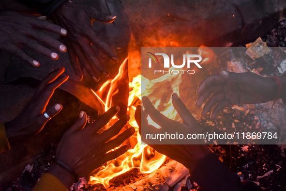 Men warm themselves by a fire on a cold winter morning in Kolkata, India, on December 15, 2024. 