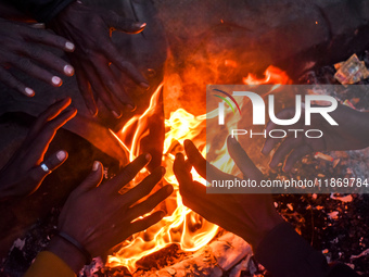 Men warm themselves by a fire on a cold winter morning in Kolkata, India, on December 15, 2024. (