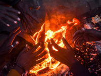 Men warm themselves by a fire on a cold winter morning in Kolkata, India, on December 15, 2024. (