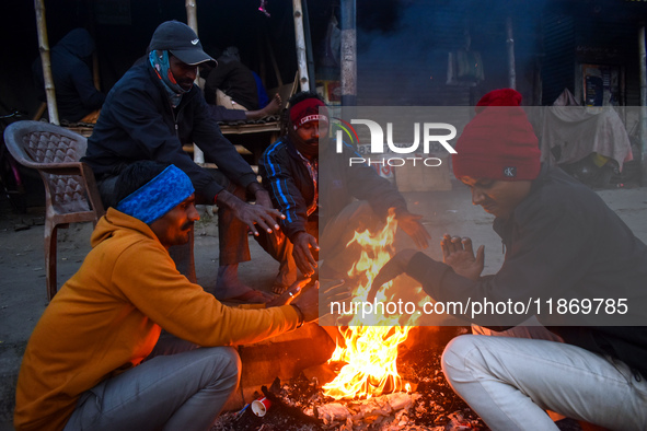 Men warm themselves by a fire on a cold winter morning in Kolkata, India, on December 15, 2024. 