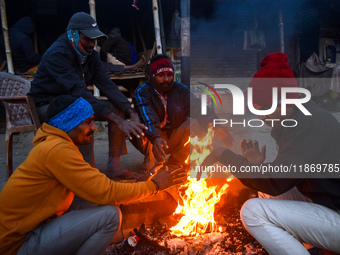 Men warm themselves by a fire on a cold winter morning in Kolkata, India, on December 15, 2024. (