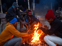 Men warm themselves by a fire on a cold winter morning in Kolkata, India, on December 15, 2024. (