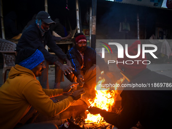 People warm themselves by a fire on a cold winter morning in Kolkata, India, on December 15, 2024. (