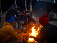 People warm themselves by a fire on a cold winter morning in Kolkata, India, on December 15, 2024. (