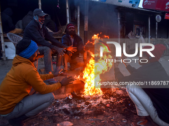 People warm themselves by a fire on a cold winter morning in Kolkata, India, on December 15, 2024. (