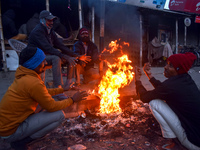 People warm themselves by a fire on a cold winter morning in Kolkata, India, on December 15, 2024. (