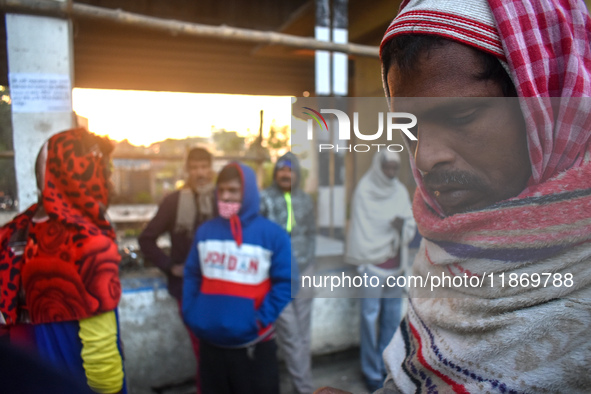 People stand beside the road on an early winter morning in Kolkata, India, on December 15, 2024. 