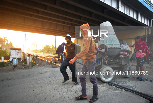 Laborers pull a construction machine to cross a railway track in Kolkata, India, on December 15, 2024. 