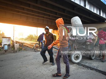 Laborers pull a construction machine to cross a railway track in Kolkata, India, on December 15, 2024. (