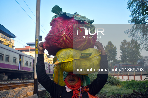 A vegetable seller carries vegetables on his head and goes towards the market in Kolkata, India, on December 15, 2024. 