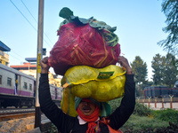 A vegetable seller carries vegetables on his head and goes towards the market in Kolkata, India, on December 15, 2024. (