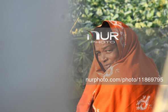 A woman covers her face with a woolen shawl while sitting in the sunlight on an early winter morning in Kolkata, India, on December 15, 2024...