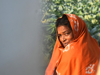 A woman covers her face with a woolen shawl while sitting in the sunlight on an early winter morning in Kolkata, India, on December 15, 2024...