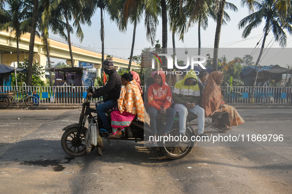 People travel on a motor cart on an early winter morning in Kolkata, India, on December 15, 2024. 