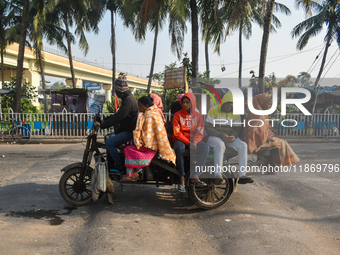 People travel on a motor cart on an early winter morning in Kolkata, India, on December 15, 2024. (