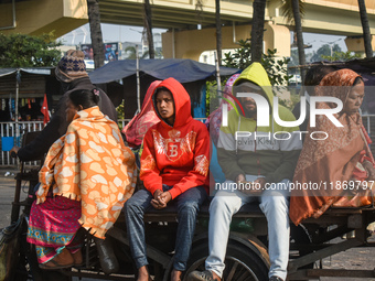 People travel on a motor cart on an early winter morning in Kolkata, India, on December 15, 2024. (