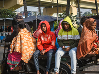 People travel on a motor cart on an early winter morning in Kolkata, India, on December 15, 2024. (