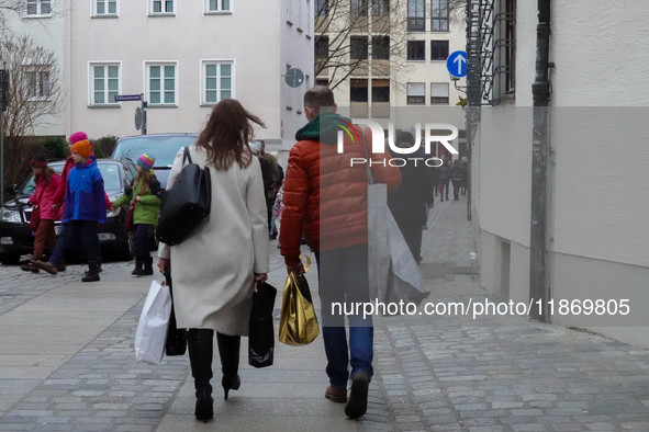 In Nuremberg, Bavaria, Germany, on December 14, 2024, a couple walks along a cobblestone street. The man, dressed in a bright orange jacket,...