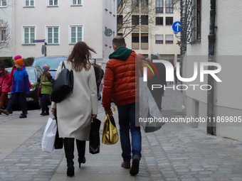 In Nuremberg, Bavaria, Germany, on December 14, 2024, a couple walks along a cobblestone street. The man, dressed in a bright orange jacket,...