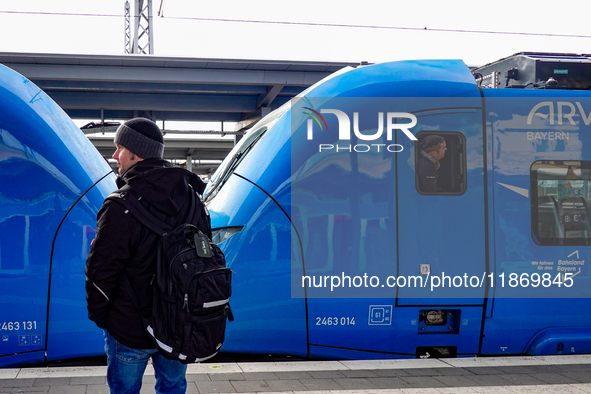 A passenger with a backpack waits on the platform as an Arverio regional train is stationed at Augsburg Central Station in Bavaria, Germany,...