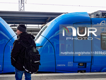 A passenger with a backpack waits on the platform as an Arverio regional train is stationed at Augsburg Central Station in Bavaria, Germany,...