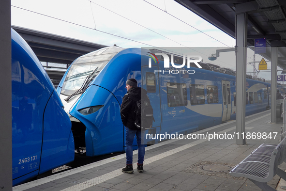 A traveler carrying a backpack waits next to an Arverio regional train at Augsburg Central Station in Bavaria, Germany, on December 14, 2024...