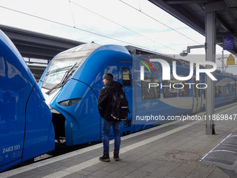 A traveler carrying a backpack waits next to an Arverio regional train at Augsburg Central Station in Bavaria, Germany, on December 14, 2024...