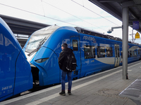 A traveler carrying a backpack waits next to an Arverio regional train at Augsburg Central Station in Bavaria, Germany, on December 14, 2024...