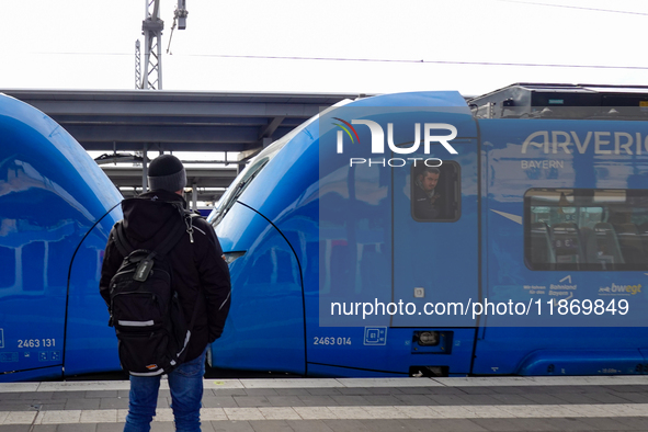 A passenger with a backpack waits on the platform as an Arverio regional train is stationed at Augsburg Central Station in Bavaria, Germany,...