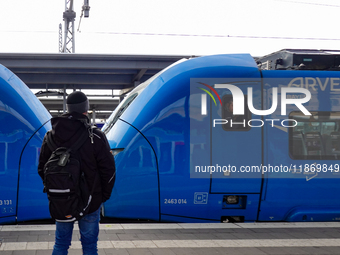 A passenger with a backpack waits on the platform as an Arverio regional train is stationed at Augsburg Central Station in Bavaria, Germany,...