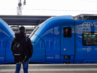 A passenger with a backpack waits on the platform as an Arverio regional train is stationed at Augsburg Central Station in Bavaria, Germany,...