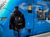 A traveler carrying a backpack waits next to an Arverio regional train at Augsburg Central Station in Bavaria, Germany, on December 14, 2024...