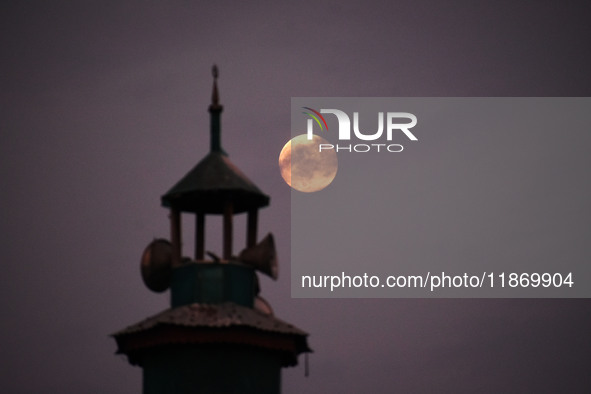 The final full moon, or cold moon, rises behind the minaret of a mosque in Srinagar, Kashmir, India, on December 14, 2024. In India, reports...