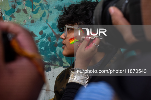 A participant paints pride flags on the cheeks of others during the annual pride walk in Kolkata, India, on December 15, 2024. 