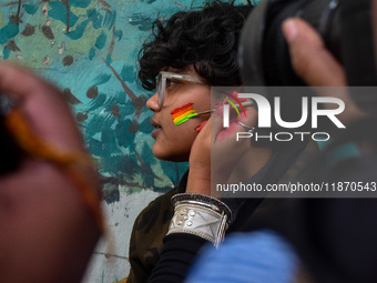 A participant paints pride flags on the cheeks of others during the annual pride walk in Kolkata, India, on December 15, 2024. (